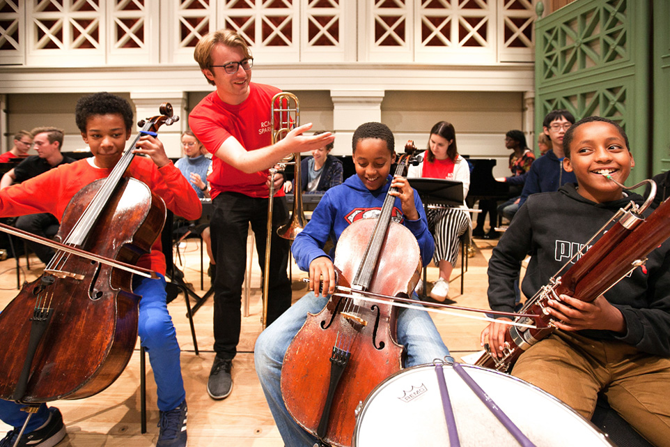 A young student performing on a cello, in a sparks rehearsal